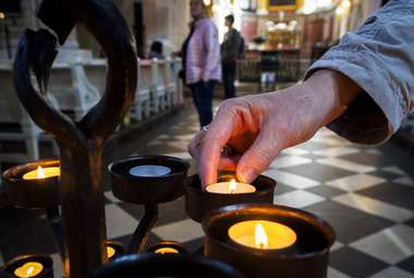 A woman lights a candle in the Church of St. Nicholas in Leipzig, Germany. (AP Photo/Jens Meyer)